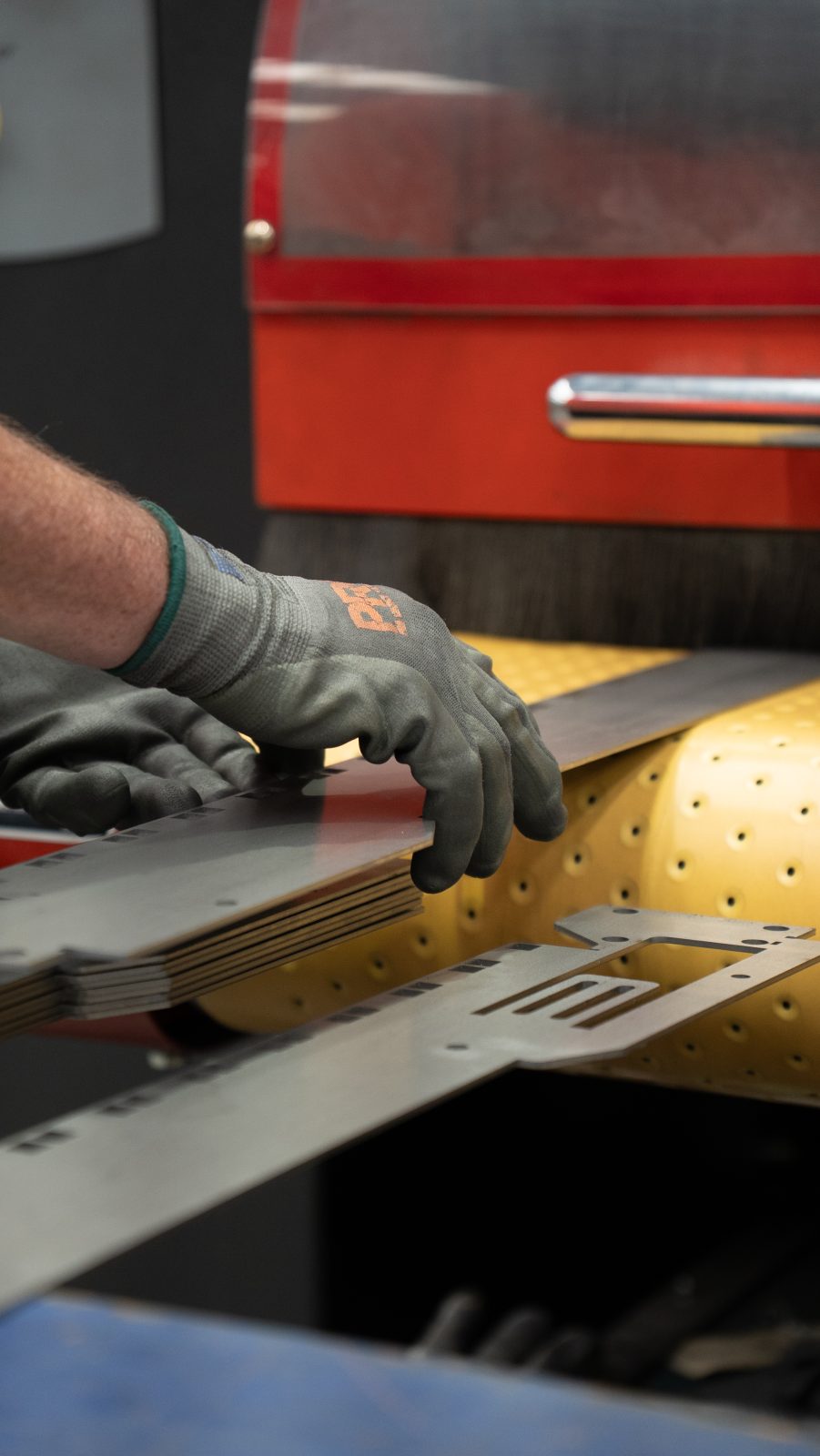 Gloved hands feeding a part through the finishing machine
