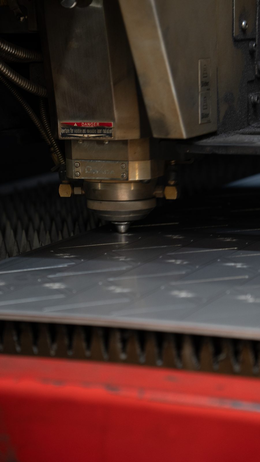 Close-up of the fibre laser cutting head over a steel sheet
