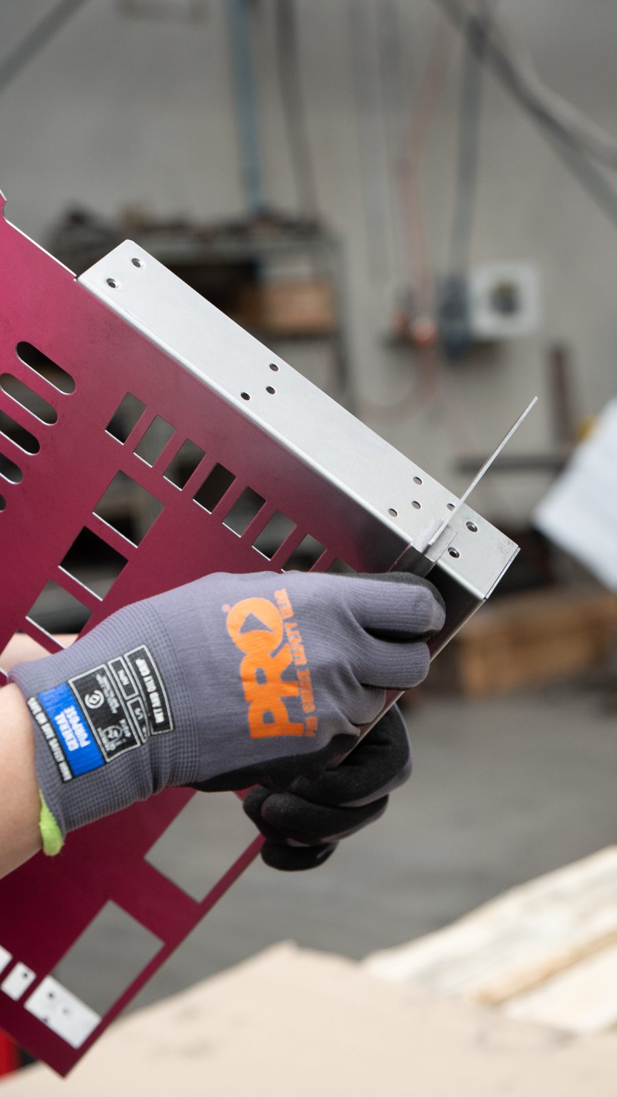 Gloved hands holding a precision-folded steel bracket